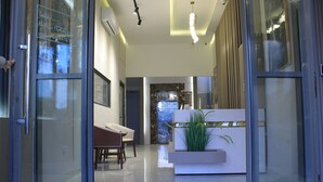 A modern interior with a reception desk, seating area, and a glass door entrance. - Azmal Hotel & Suites (Irbid)