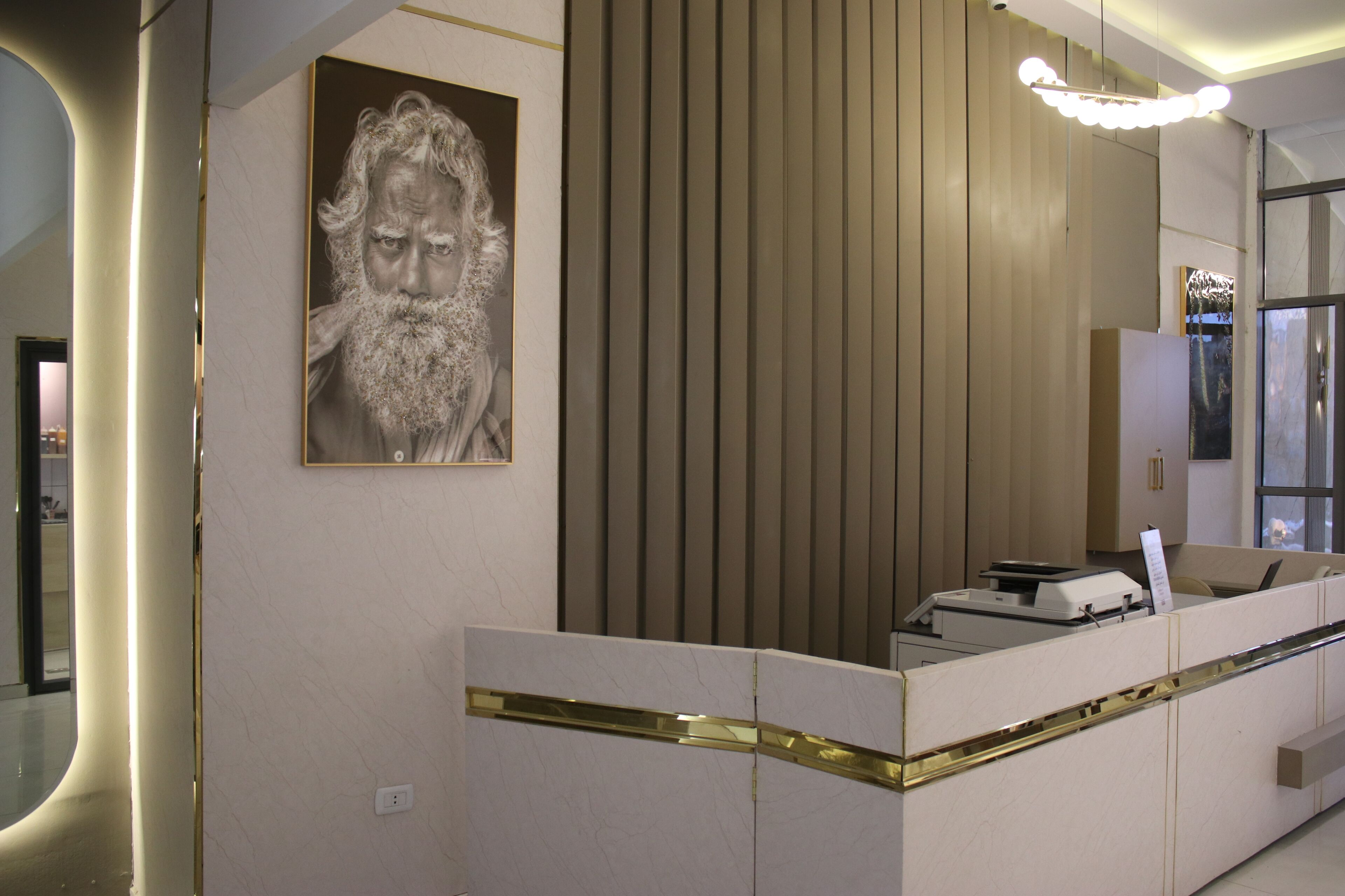 A reception desk with a modern design, a framed portrait on the wall, and a vertical wooden paneling.