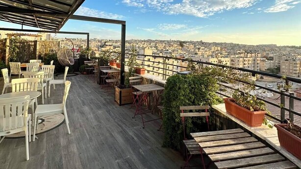 A rooftop terrace with outdoor seating, potted plants, and a city view. - Azmal Hotel & Suites (Irbid)