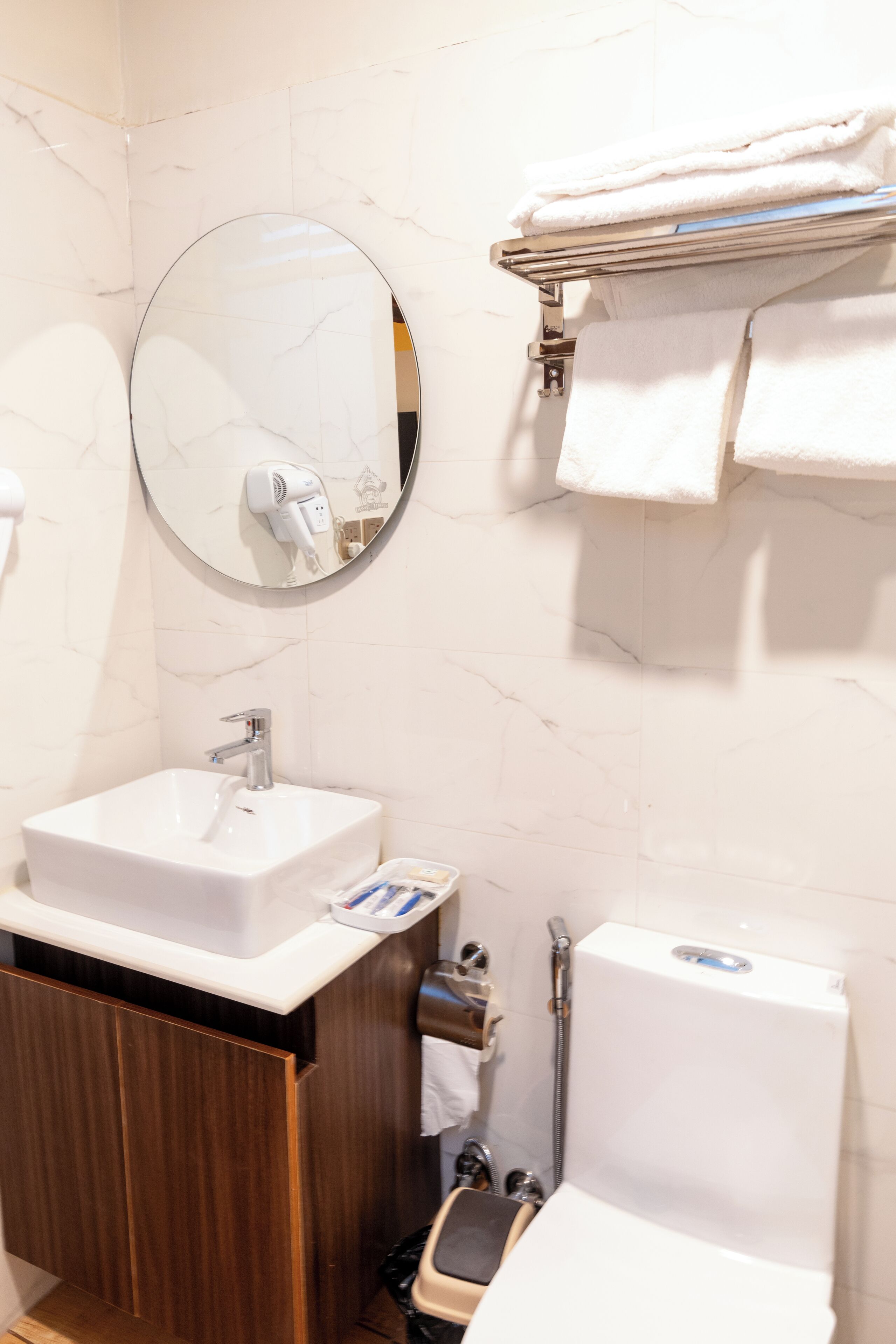 A bathroom with a white sink, mirror, and towel rack.