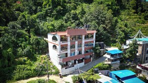 A multi-story building with balconies, surrounded by lush greenery. - Monkey Temple Residence (Nagarjun)
