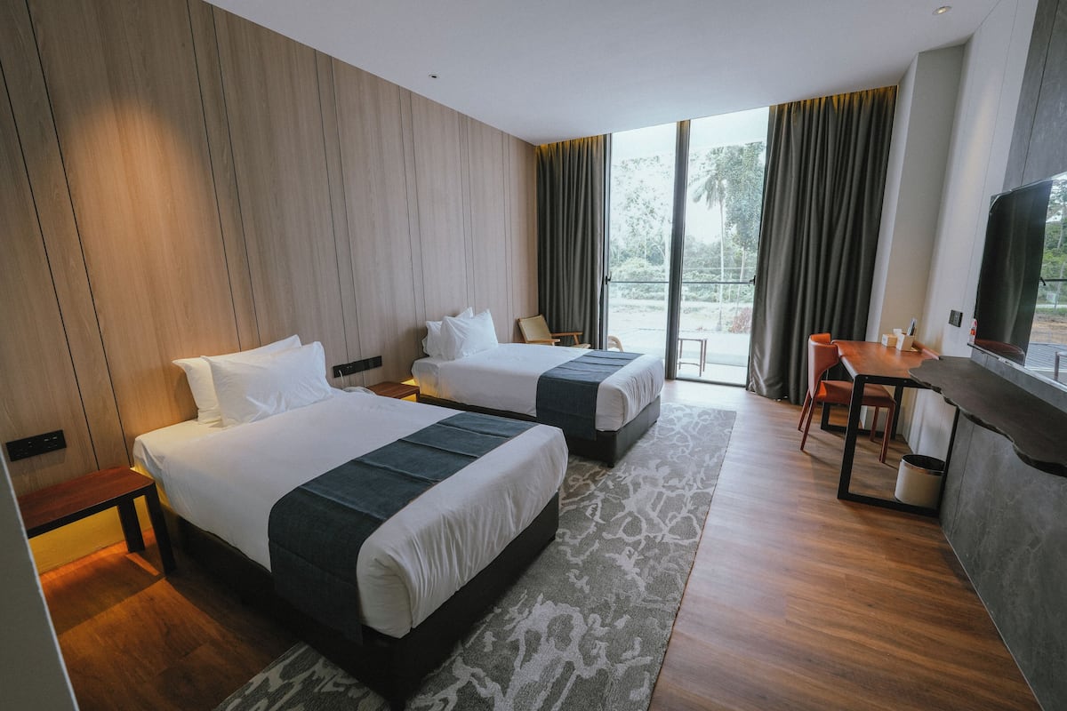 A hotel room with two beds, a desk, and a TV.