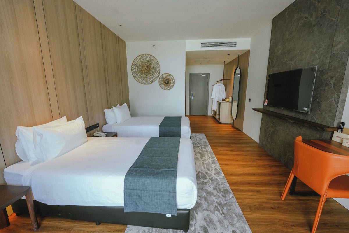 A hotel room with two beds, a TV, a desk, and a chair.