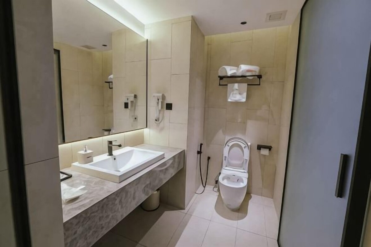 A modern bathroom with a marble sink, a toilet, and a large mirror.