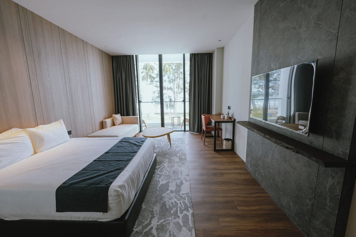 A hotel room with a large bed, a desk, a chair, and a television mounted on the wall.