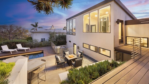 A modern house with a pool, outdoor seating, and a staircase.