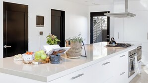 A modern kitchen with a large island, built-in oven, and stainless steel appliances.