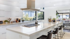 A modern kitchen with a central island, stainless steel appliances, and a large window offering a city view.