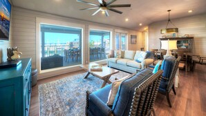 A spacious living room with a large window, a ceiling fan, and a dining area with a table and chairs.