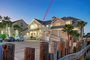 A hotel with a prominent entrance, a covered outdoor seating area, and a visible staircase leading to the entrance. - Sailfish & Dolphin Buyout by AvantStay | 2 units, Marina Front + View, Patio (Port Aransas)