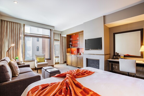 Une chambre d’hôtel avec un grand lit, un canapé, un bureau, une télévision et un coin cuisine.