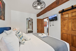 Une chambre à coucher avec un lit, un miroir, une télévision et des portes en bois.