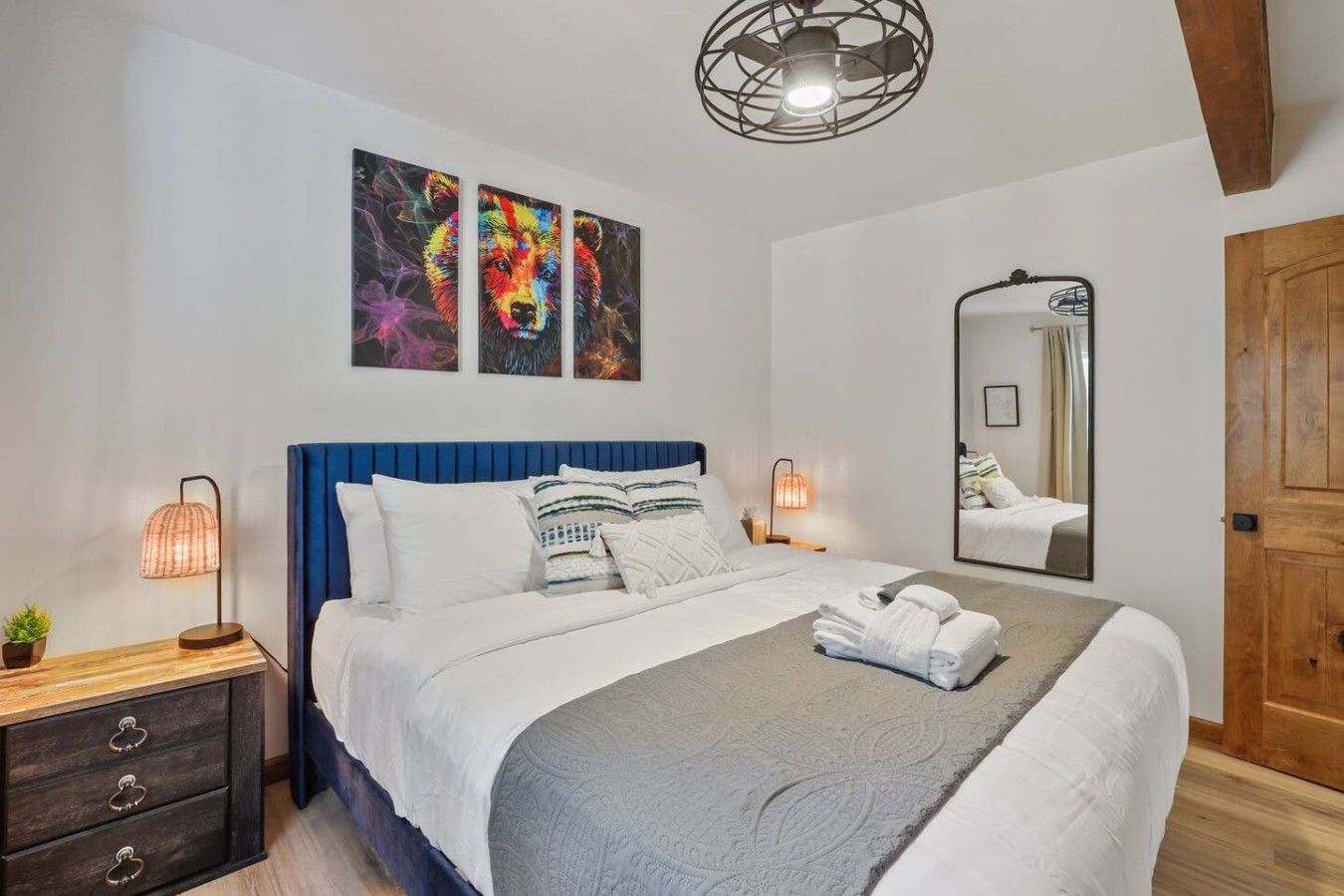 Une chambre à coucher avec un lit, des lampes de chevet, un miroir et des œuvres d’art accrochées au mur.