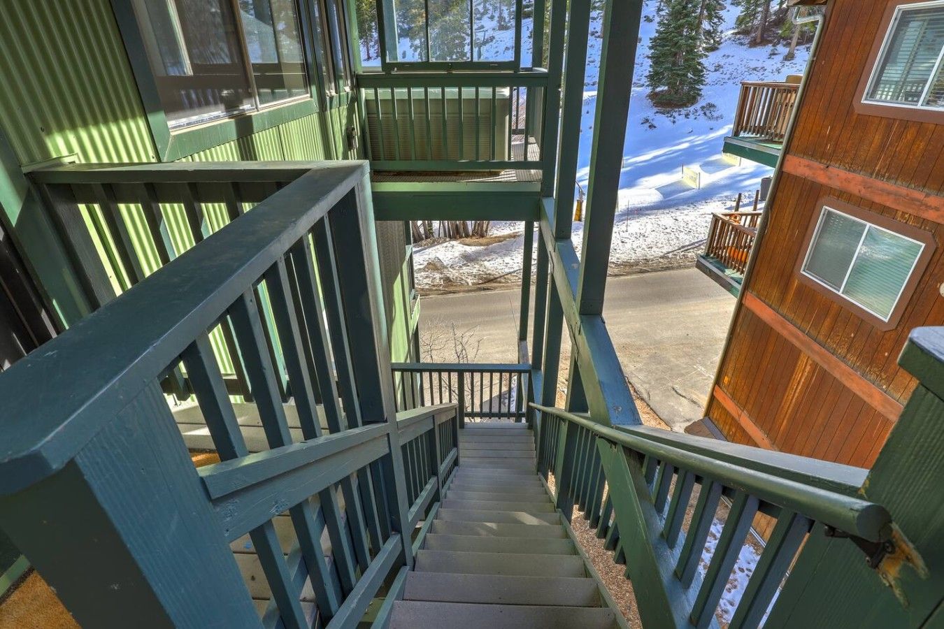 A staircase leading to a wooden cabin with a view of snow-covered ground.