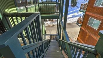 A staircase leading to a wooden cabin with a view of snow-covered ground.