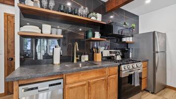 Une cuisine moderne équipée d’un lave-vaisselle, d’une cuisinière, d’un réfrigérateur et de meubles de rangement en bois.