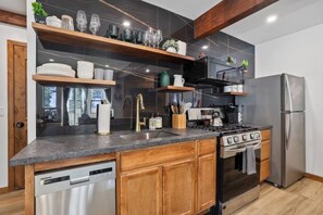 Une cuisine moderne équipée d’un lave-vaisselle, d’une cuisinière, d’un réfrigérateur et de meubles de rangement en bois.