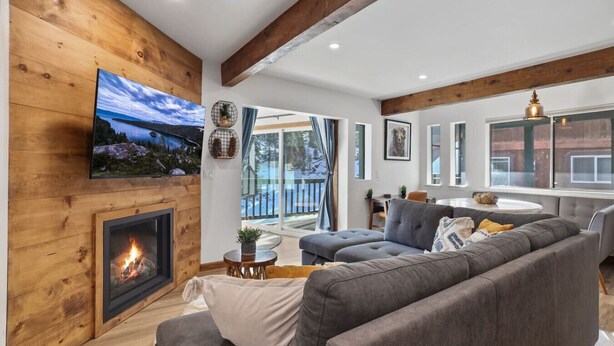 Un salon moderne avec une cheminée, un canapé gris et un téléviseur fixé à un mur en bois.