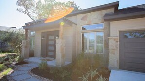 A modern house with a stone facade, a covered porch, and a garage. - Luxury New Build - 7 Beds! (Bryan)