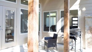 A spacious patio area with a seating arrangement, large windows, and a grill station. - Luxury New Build - 7 Beds! (Bryan)