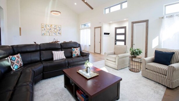 A spacious living room with a black leather sofa, a wooden coffee table, and striped armchairs. - Luxury New Build - 7 Beds! (Bryan)