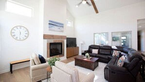A spacious living room with a fireplace, leather sofas, a coffee table, and a large clock on the wall. - Luxury New Build - 7 Beds! (Bryan)