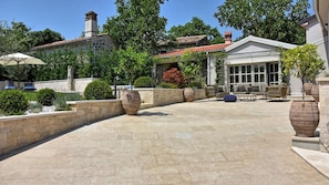 A patio area with stone flooring, outdoor furniture, and large planters. - Villa Zita by Villas Guide (Pican)
