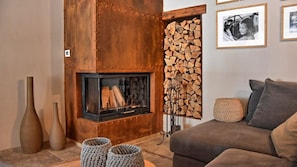 A cozy living room with a fireplace, a sofa, and a wall-mounted photo frame.