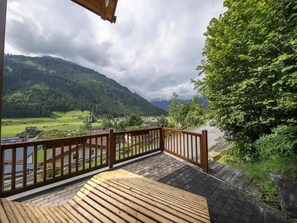 A wooden deck with a view of a valley and mountains. - Panoramic Cottage in Wald im Pinzgau (Wald im Pingzau)