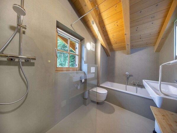 Ein modernes Badezimmer mit Dusche, Toilette und Badewanne.