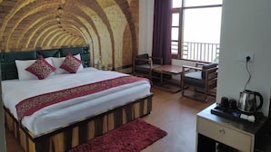 Um quarto com teto abobadado de tijolos, uma cama com cabeceira verde, uma mesinha de cabeceira de madeira e uma janela com cortinas.