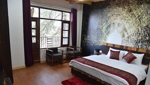 Quarto com cama grande, escrivaninha e cadeira. Há uma janela com cortinas e um mural na parede.