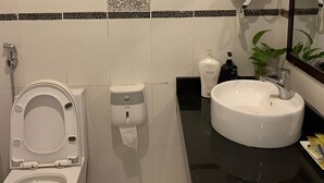A modern bathroom with a toilet, hand dryer, and sink. - Hoang Lan Hotel KDT Xala HN - BAY LUXURY (Hanoi)