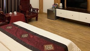 A hotel room with a bed, a TV, a small table with a kettle, and a chair. - Hoang Lan Hotel KDT Xala HN - BAY LUXURY (Hanoi)