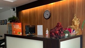 A reception desk with a clock, a plant, and a statue. - Hoang Lan Hotel KDT Xala HN - BAY LUXURY (Hanoi)