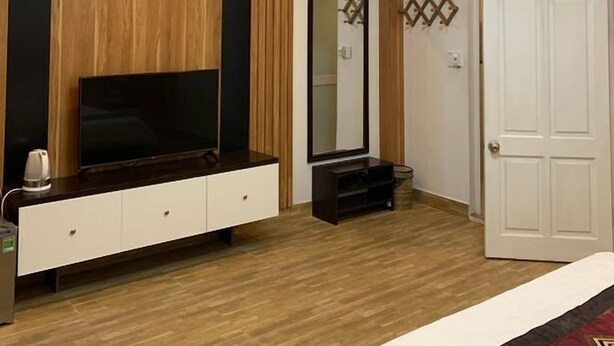 A modern bedroom with a TV, built-in air conditioning, a mirror, and a wardrobe. - Hoang Lan Hotel KDT Xala HN - BAY LUXURY (Hanoi)