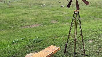 Un molino de viento en un campo cubierto de hierba, con un banco de madera y un tronco cerca.