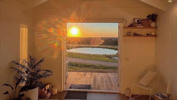 A room with a large window, a ceiling fan, and a bed.