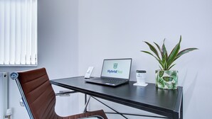 A modern office space with a laptop on a desk, a potted plant, and a chair.