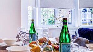 A dining table set with bowls, glasses, and bottles, with a window view in the background. - Hybrid Resi - New Malden | 3 Bed Apartment (New Malden)
