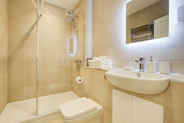 Une salle de bain moderne avec une douche à parois de verre, un lavabo blanc et des toilettes.