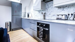 A modern kitchen with a marble backsplash, stainless steel appliances, and a skylight. - Hybrid Resi - New Malden | 1 Bed Apartment (New Malden)