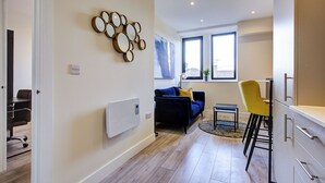 Een moderne woonkamer met een blauwe bank, een gele fauteuil en een eethoek met een tafel en stoelen.