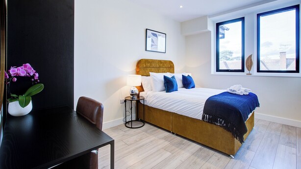 Een moderne hotelkamer met een houten bed, een bureau en een raam met uitzicht op de stad.