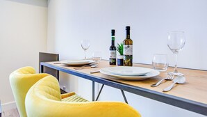 Een eettafel gedekt met borden, bestek en twee flessen wijn, omringd door gele stoelen.