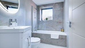 A modern bathroom with a toilet, sink, and bathtub. - Hybrid Resi - Uxbridge|1 Bed Apartment (Uxbridge)