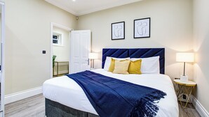 Ein ordentlich eingerichtetes Hotelzimmer mit einem großen Bett, zwei Nachttischlampen und gerahmten Bildern an der Wand.