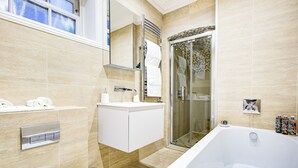 Ein modernes Badezimmer mit einer großzügigen Badewanne, einer Duschkabine aus Glas und einem Waschtisch mit Spiegel.