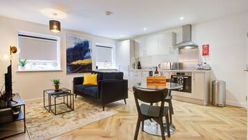 A modern apartment with a living room, dining area, and kitchen. It features a sofa, a coffee table, a dining table, and a kitchen with cabinets and appliances.