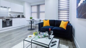 Ein modernes Wohnzimmer mit einem dunkelblauen Sofa, einem Couchtisch und einem Essbereich mit kleinem Tisch und Stühlen.